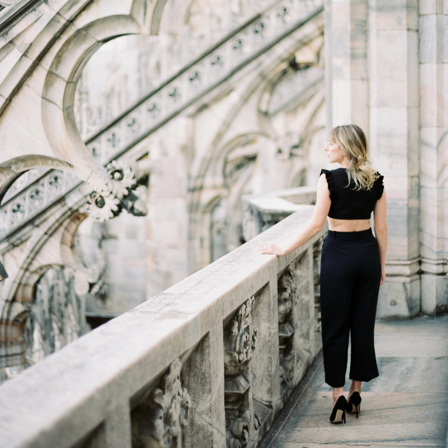 girl dressed in black walking across a bridge